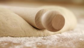 Close up of rolling pin on dough