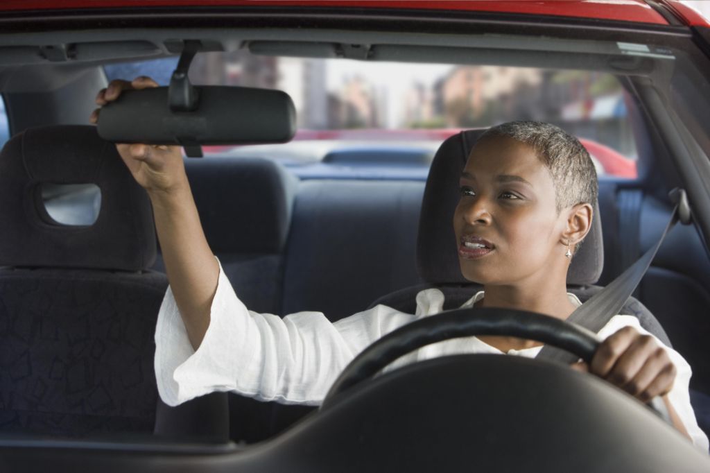 African woman in car adjusting mirror