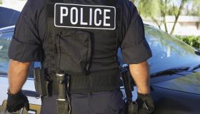 Police officer in bulletproof vest outdoors, back view
