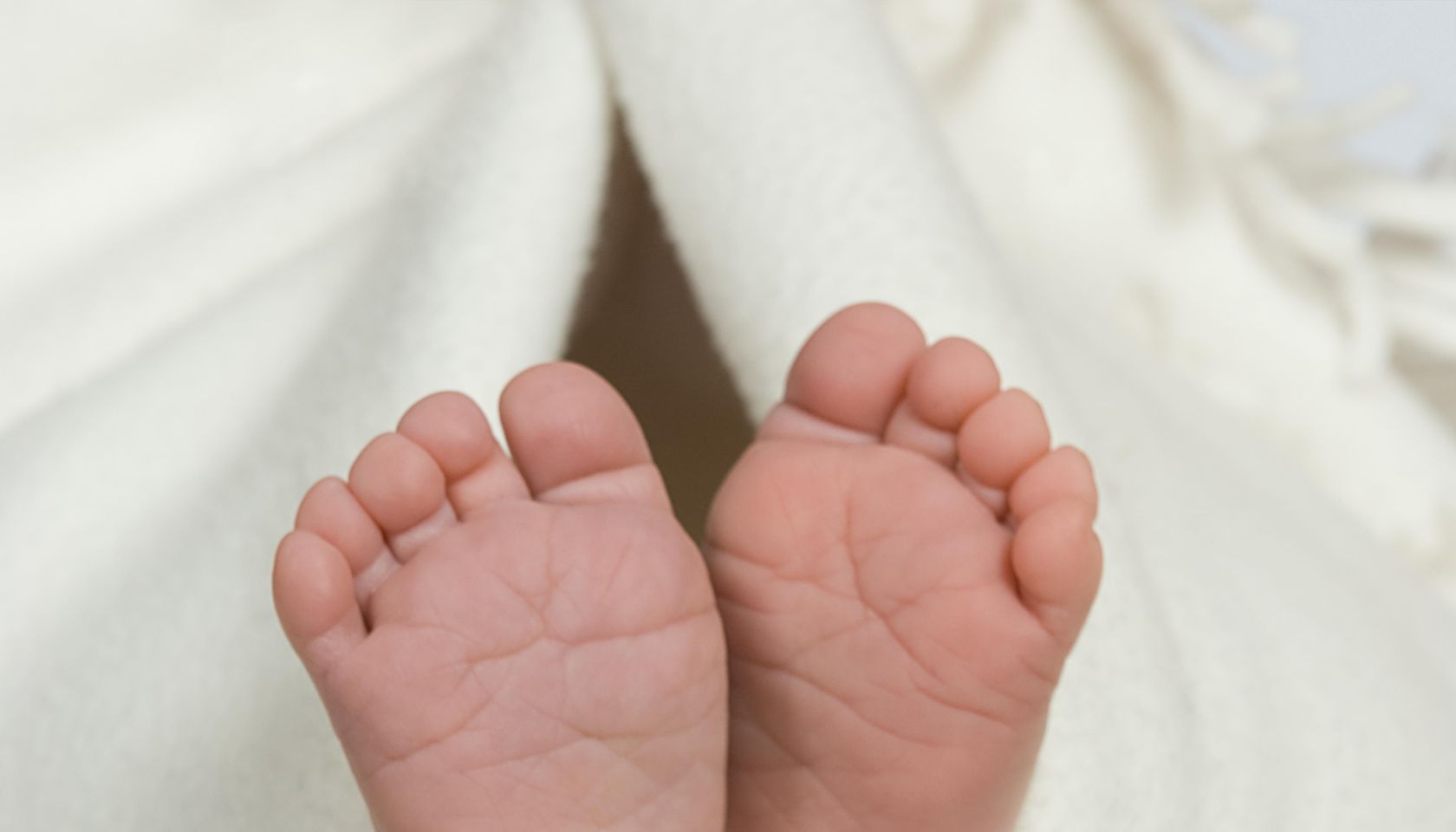 Pair of baby's feet poking out from blanket, close-up
