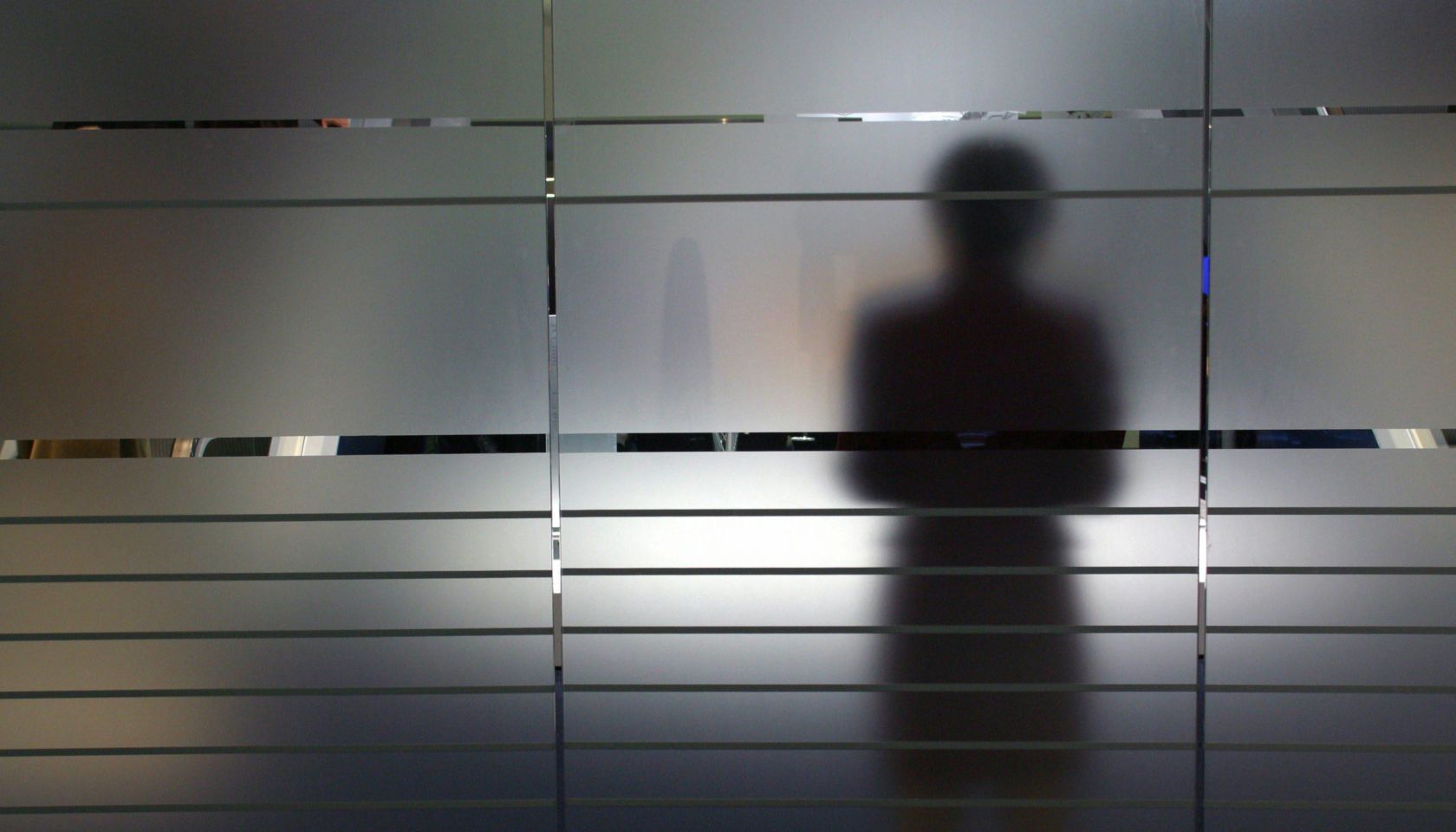 Shadow of a woman on a frosted glass pane, Symbolic photo to the topics: anonymity, fear, uncertainty, unsteadiness, personal secrets etc.