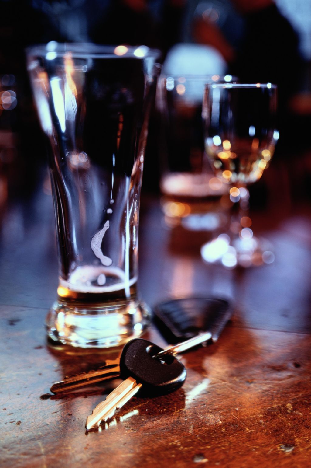 Set of car keys lying beside lager glass on bar