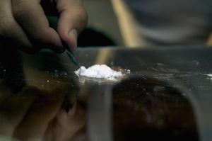 Close-up of a man's hand cutting cocaine with a blade