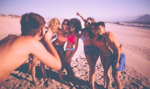 Guy taking a picture of group of friends on beach