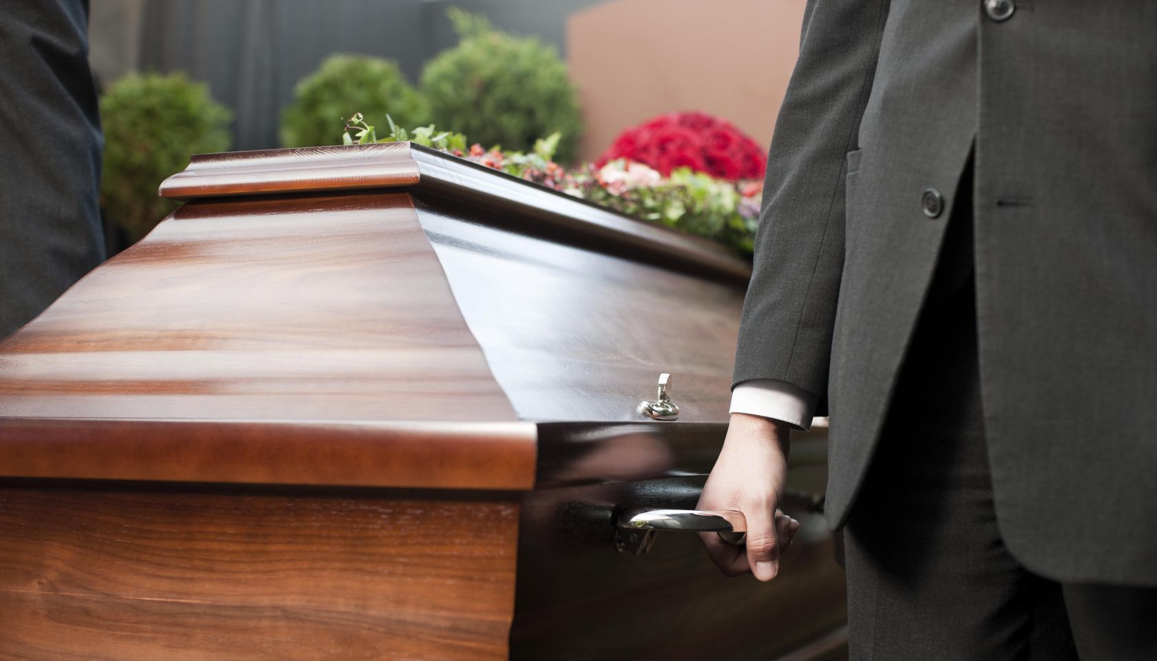 Religion, death and dolor - coffin bearer carrying casket at funeral to cemetery