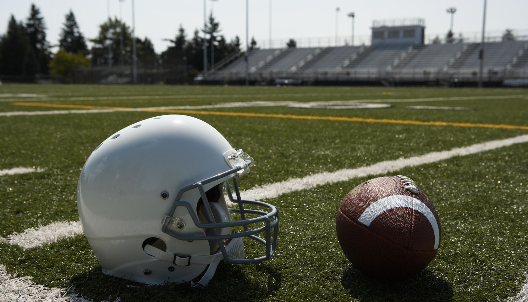 Football and football helmet on football field
