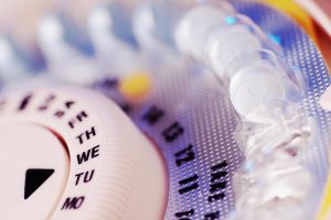 Birth control pills in plastic tablet dispenser case