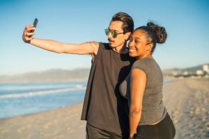 Young couple, Latino man and girl, take selfie on beach