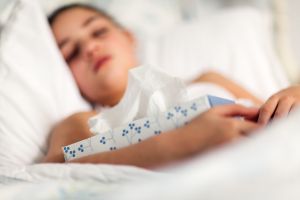 Girl in bed holding box of tissues