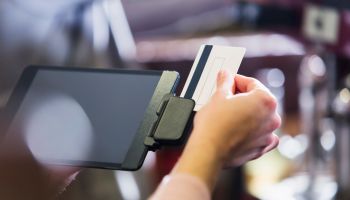 Hand of woman sliding credit card through reader