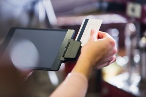 Hand of woman sliding credit card through reader