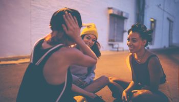 Teen girls sitting on street at night talking and laughing