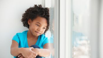 Black girl sitting in windowsill