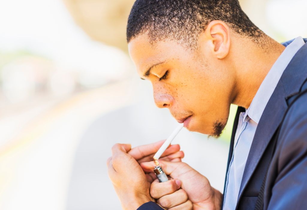 Black businessman lighting cigarette outdoors