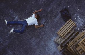 Man with gun lying on ground, chalk outline around him, elevated view