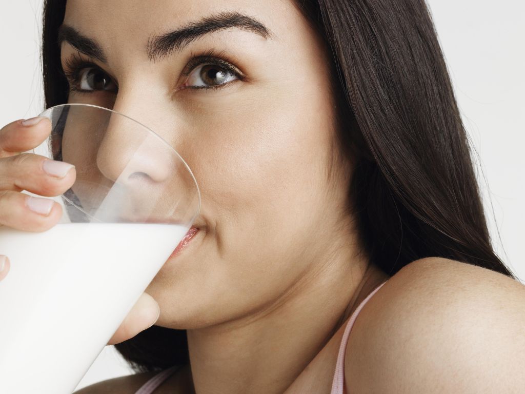 Young woman drinking milk, looking away, portrait, close-up