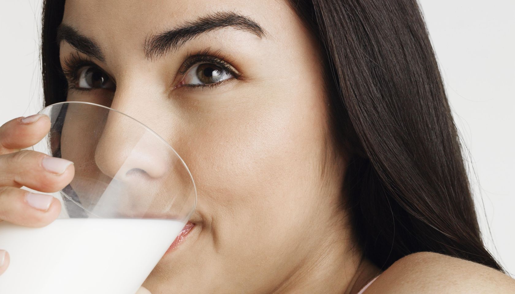Young woman drinking milk, looking away, portrait, close-up