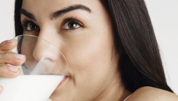 Young woman drinking milk, looking away, portrait, close-up