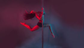 Young Pole Dancer Performing Against Colored Background