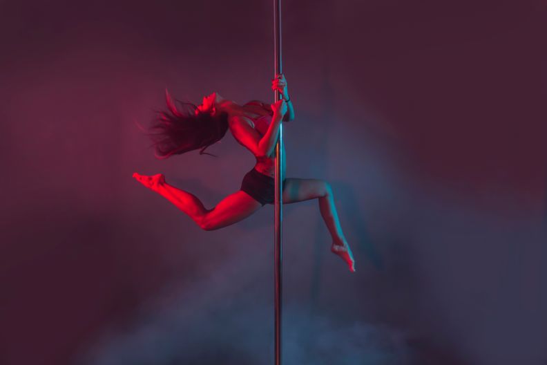 Young Pole Dancer Performing Against Colored Background