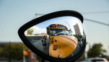 Photographer Taking Self Portrait In Side-View Mirror Of School Bus