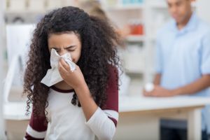 African American preteen girl uses tissue in pharmacy