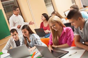 Happy professor talking to female student during computer class.