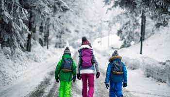 Kids with backpacks walking on winter road