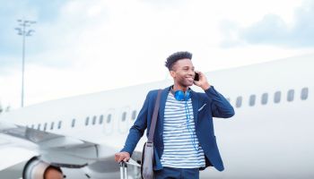 Young businessman talking on smart phone in front of airplane