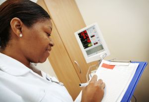 Nurse in white uniform writing updates to her patients records