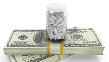 White pills on top of dollar bills bundle. High cost of healthcare concept