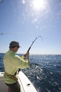 Man with Sailfish on bending fishing rod on boat.