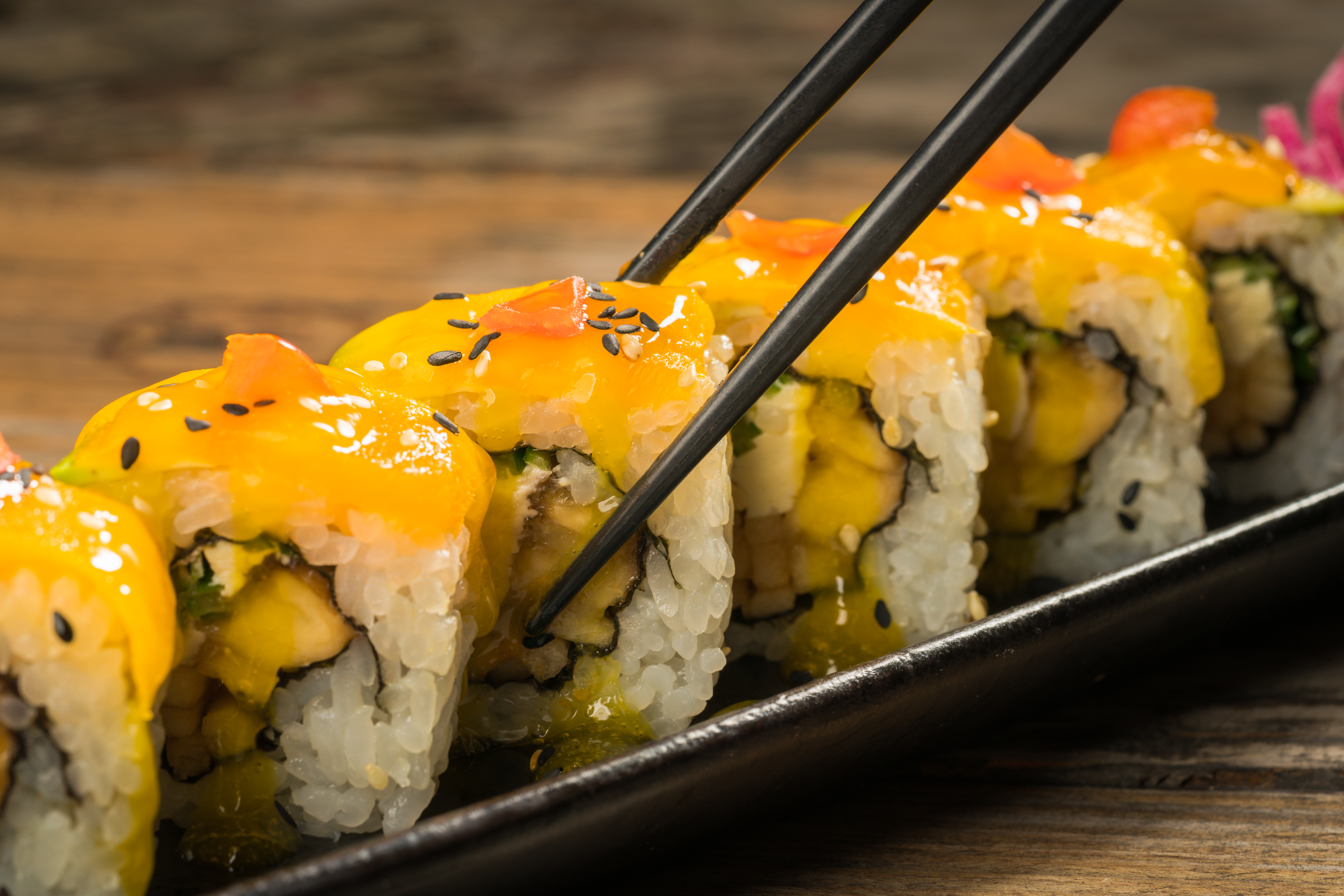 Yellow sushi roll with chopstick on the plate.