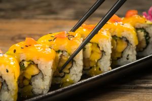 Yellow sushi roll with chopstick on the plate.