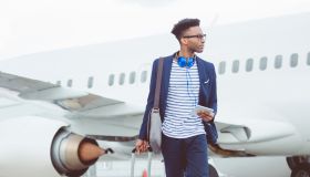 Young african businessman walking in front of airplane