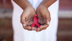Child's hands holding an HIV awareness ribbon, Cape Town, South Africa