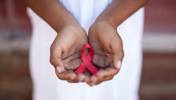 Child's hands holding an HIV awareness ribbon, Cape Town, South Africa