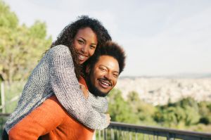 Spain, Barcelona, portrait of happy young man giving his girlfriend a piggyback ride