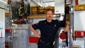 Firefighter leaning against rear of fire engine, portrait