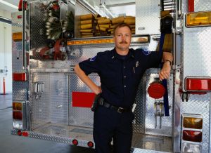 Firefighter leaning against rear of fire engine, portrait