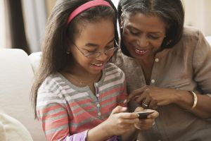 African American grandmother and granddaughter looking at cell phone