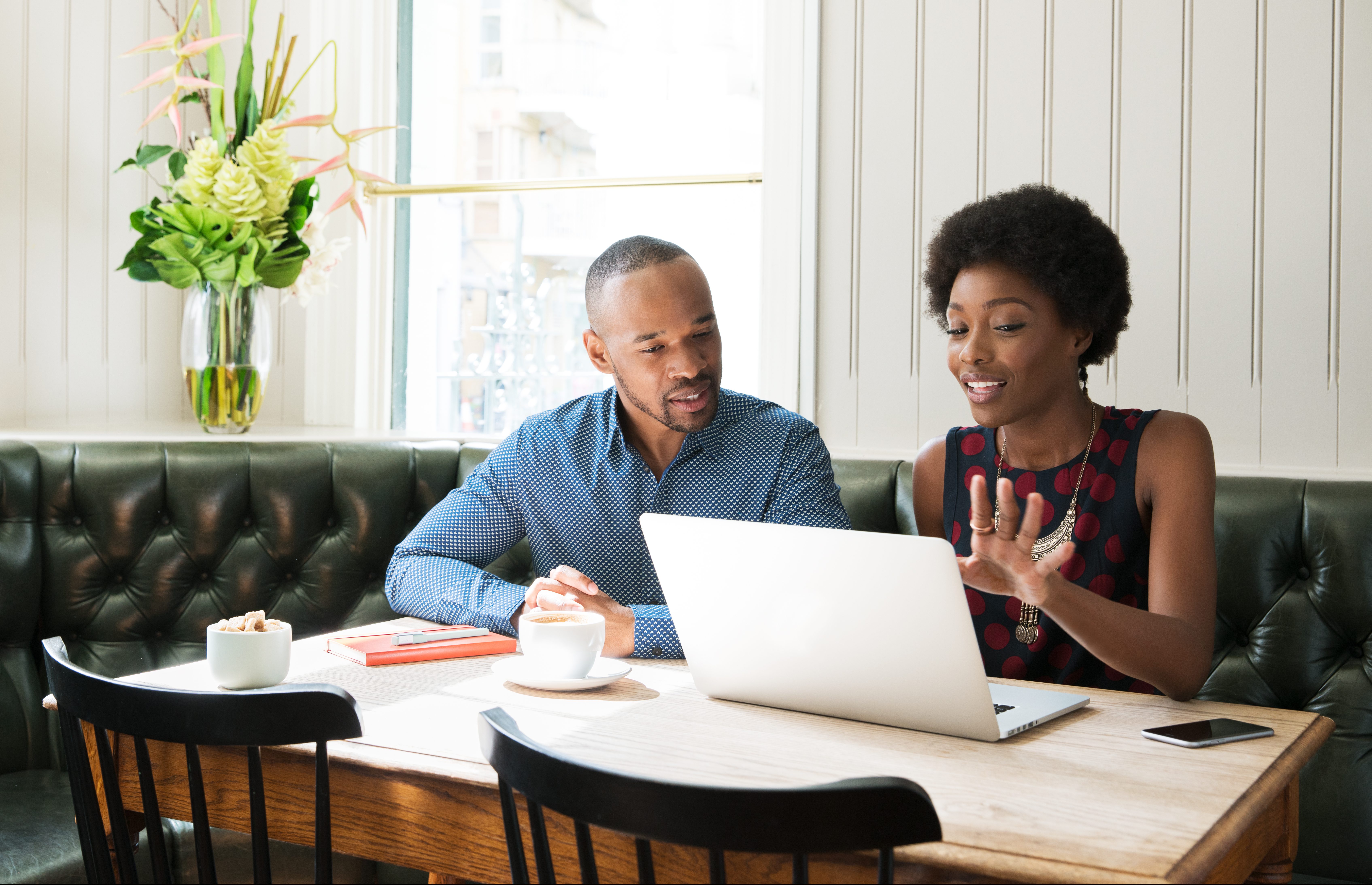 Two people using laptop at table.