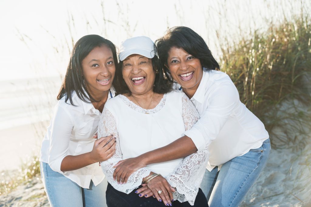 Three generations of black women posing on beach