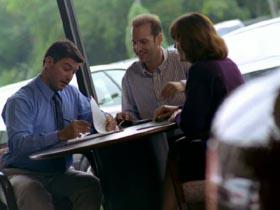 dolly shot zoom in CANTED salesman fillout out forms with couple in car dealership