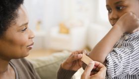 Black mother putting bandage on son's elbow