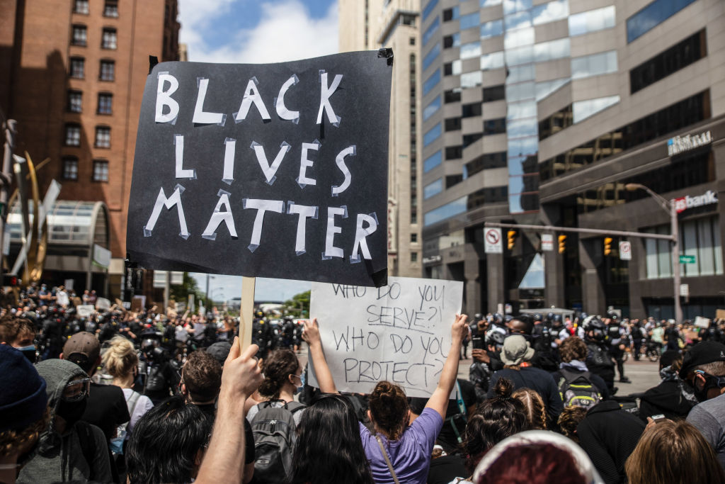A protester holds a placard that says Black Lives Matter...