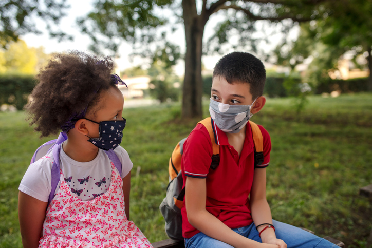 School kids in schoolyard wearing face protective mask