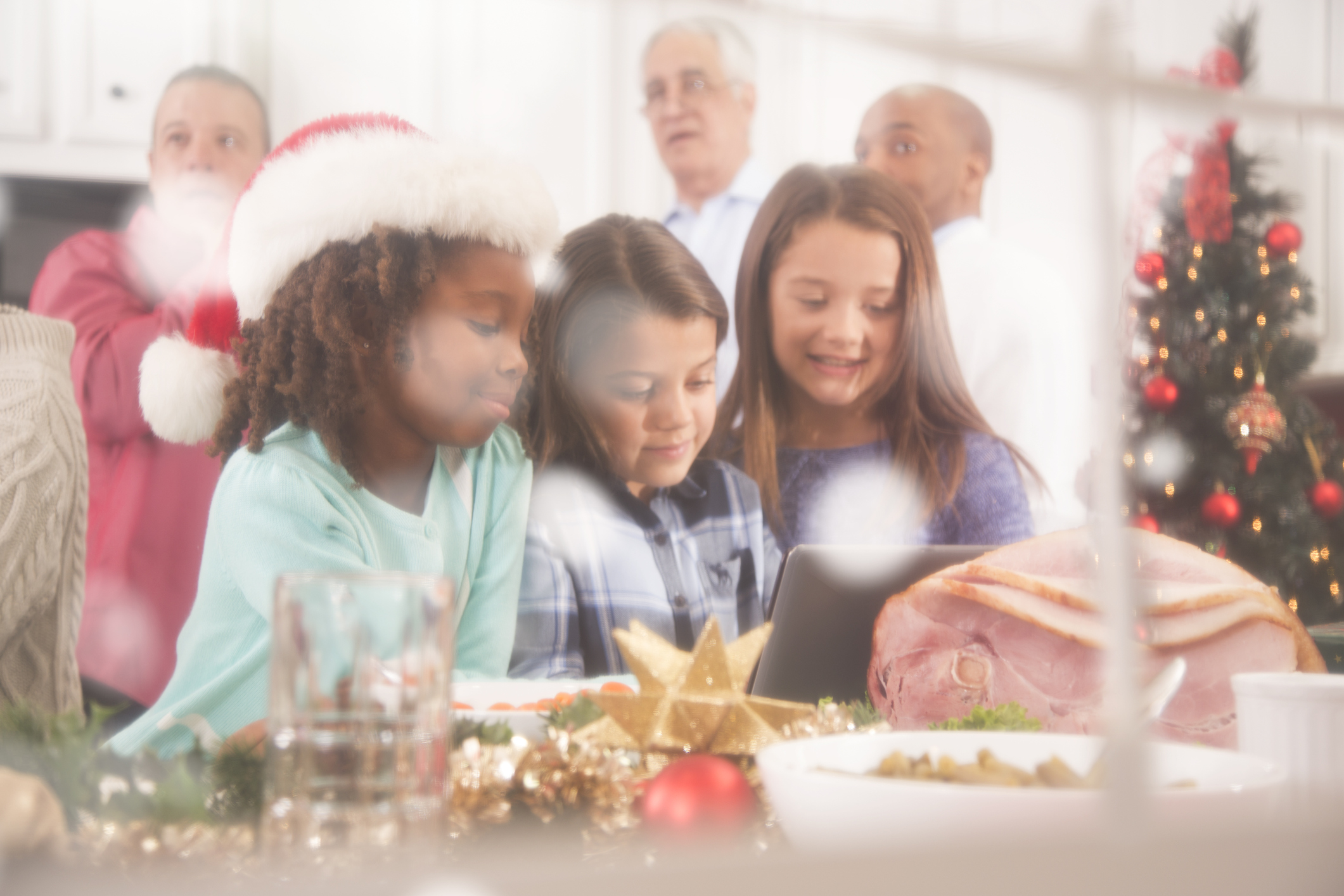 View through snowy window of family in home kitchen at Christmas party.