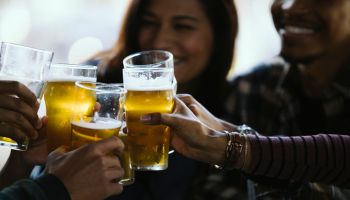 Close-up of happy friends toasting beer glasses in pub