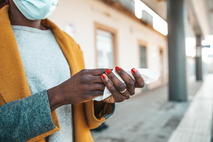 Woman sanitizing her hands waiting the train